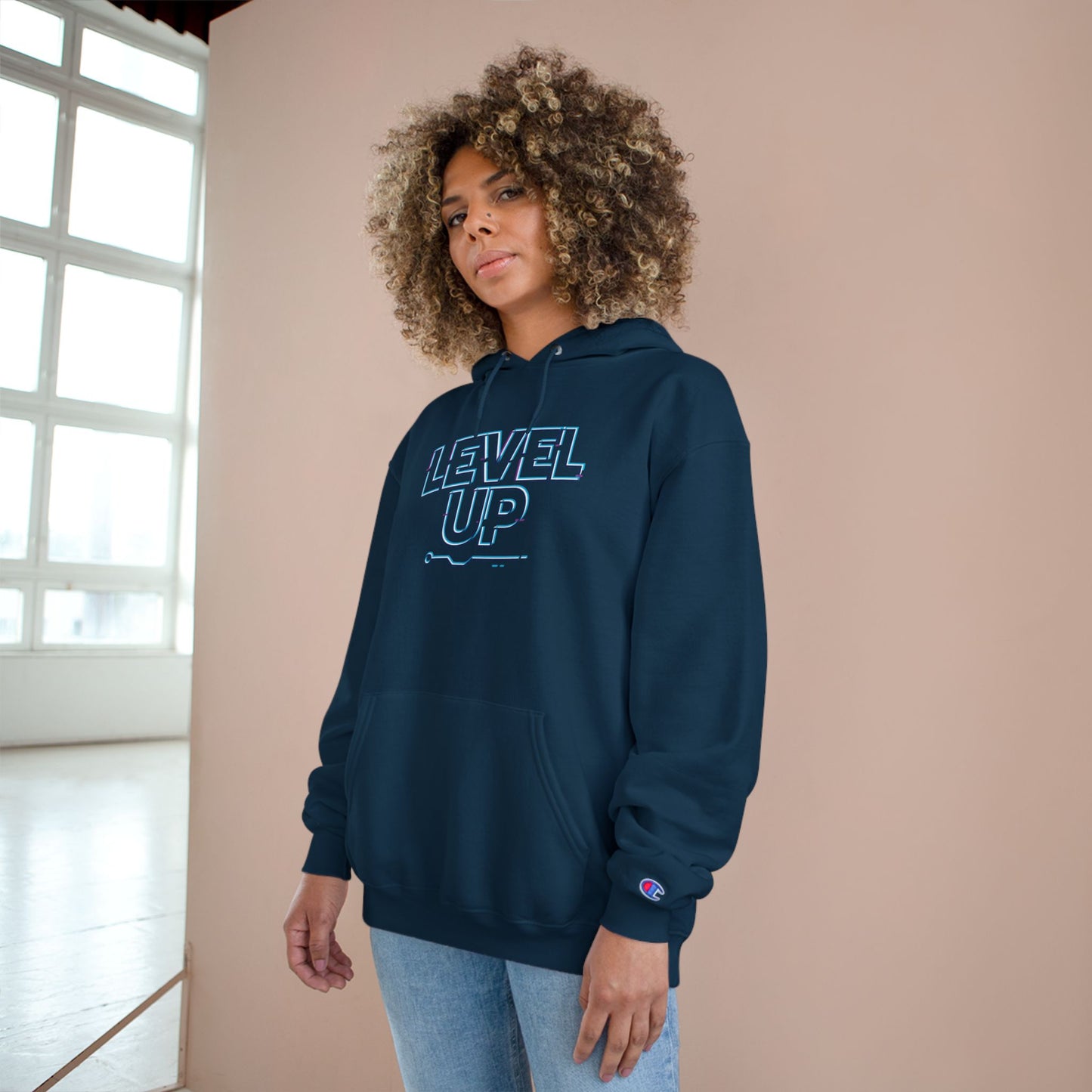 Person wearing a navy hoodie with 'LEVEL UP' text against a beige wall.