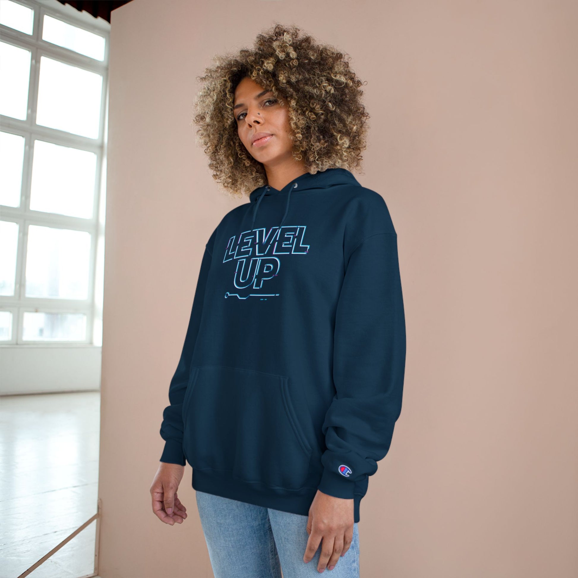 Person wearing a navy hoodie with 'LEVEL UP' text against a beige wall.