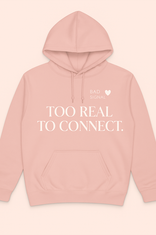 Pink womenβs hoodie with white bold text reading Too Real to Connect and small Bad Signal heart icon β minimalist streetwear by Dare 2 Wear.