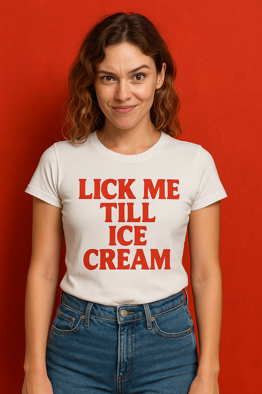 A young woman wearing a fitted white t-shirt with the bold red text “LICK ME TILL ICE CREAM” printed on the front, standing against a red background.