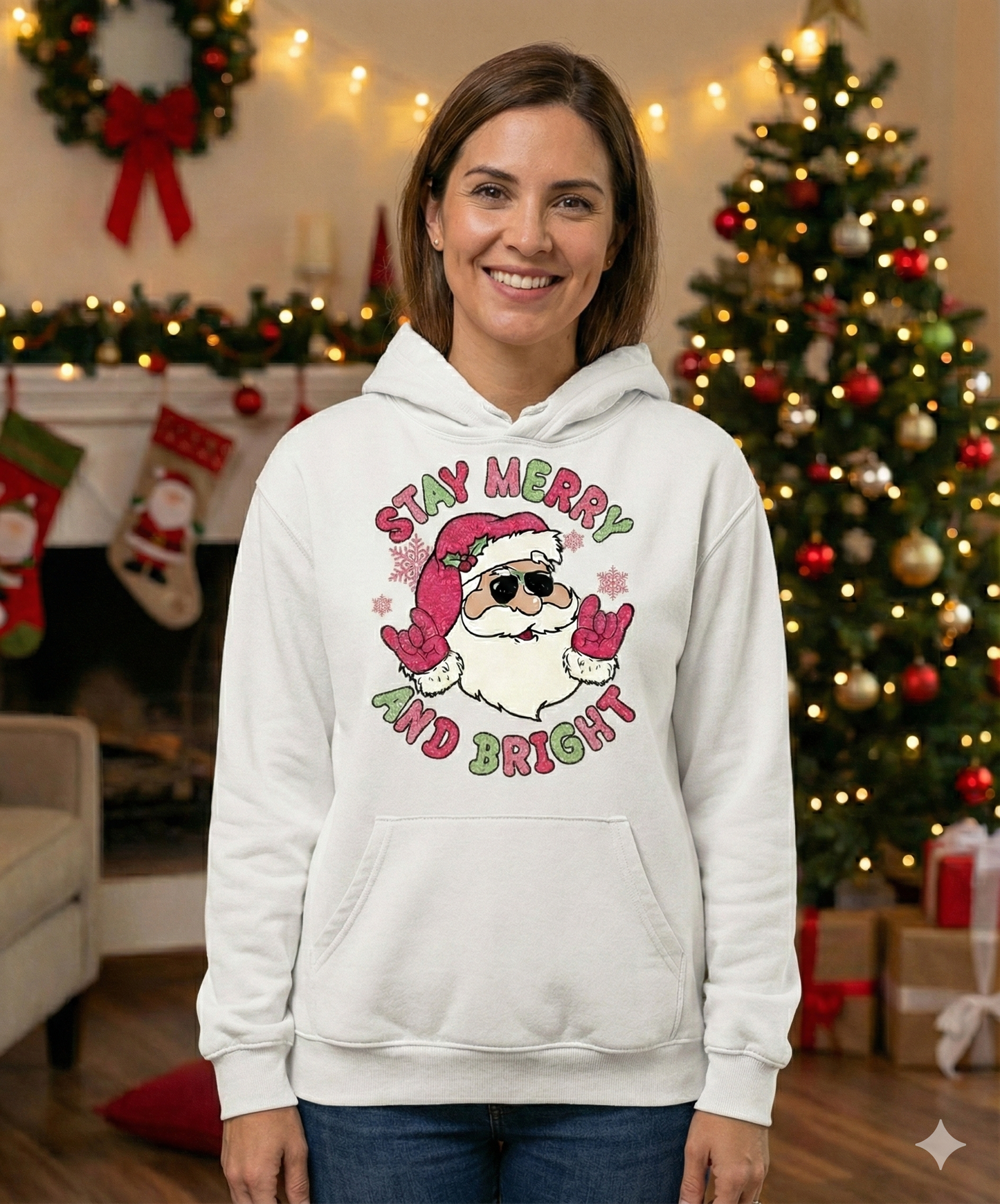 Woman wearing a white hoodie with a Christmas design in a decorated living room.