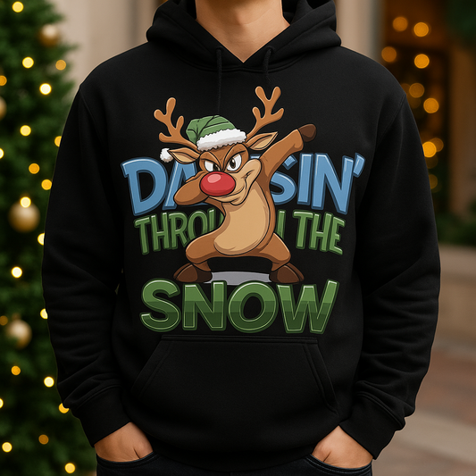 Black hoodie with a cartoon reindeer design and text 'Dabbin' through the snow' in front of a blurred Christmas tree.